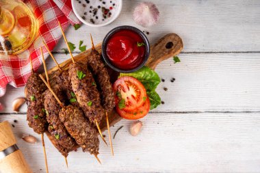 Çubuklu şiş kebap, kıymalı kıymadan yapılır. Lula kebap, geleneksel Kafkas yemeği, ketçap, baharat ve sebze salatası, barbekü ızgara pişirme arka planı fotokopi alanı yukarıda. 