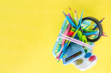 Okulun çeşitli okul gereçleri, öğrenciler ve okul çocukları için eğitim aksesuarları, defterler, kalemler, kalemler, hesap makinesi, kalem kutusu, sırt çantası, kulaklık içeren renkli geçmişine geri dön