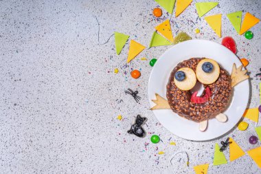 Fun Halloween Donuts. Creative decoration for chocolate donuts on Halloween  decorated table. Treat or trick holiday kid snack, white table background copy space