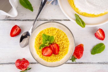 Klasik cam kaplı cheesecake, taze çilekli ve altın kurabiyeli. Katmanlı cheesecake tatlısıyla beyaz ahşap masa üzerinde taze çilekler fotokopi alanı