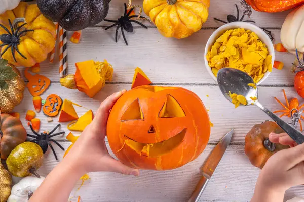 Balkabağı oyma Jack Feneri ile Cadılar Bayramı hazırlığı. Kadın, kadın ve çocuklar ellerini çerçeveye koyar, dekore eder, çizer ve korkunç Cadılar Bayramı partisini oyar.