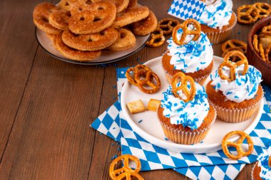 Oktoberfest kekleri tuzlu kraker, krem şanti ve renkli şeker serpintileri, beyaz ahşap arka planda Oktoberfest bayram dekoru, kopyalama alanı