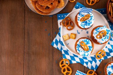 Oktoberfest kekleri tuzlu kraker, krem şanti ve renkli şeker serpintileri, beyaz ahşap arka planda Oktoberfest bayram dekoru, kopyalama alanı