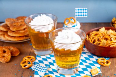 Oktoberfest tatlı fikri, üzerinde krem şanti olan renkli biralı iki bardak altın jöle pudingi, şenlikli Oktoberfest partisi ahşap masa, kopyalama alanı.