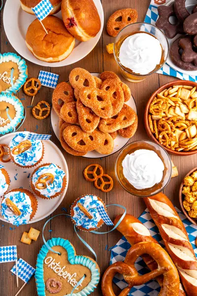 Oktoberfest festival yemekleri, çeşitli atıştırmalıklar, tatlılar, tatlılar, krakerler, bira jölesi, zencefilli kurabiye kalpleri, tuzlanmış krakerler, patlamış mısır, reçelli çörekler, kekler. Oktoberfest brunch menüsü arkaplanı