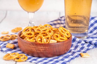 Oktoberfest tebrik kartı geçmişinde iki bira bardağı, tuzlu atıştırmalık ve kraker var. Oktoberfest barı, beyaz ahşap masa üzerindeki kafe menüsü, Ekim Festivali tarzı kareli peçete ve dekorla