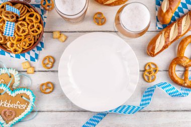 Oktoberfest tebrik kartı geçmişinde iki bira bardağı, tuzlu atıştırmalık ve kraker var. Oktoberfest barı, beyaz ahşap masa üzerindeki kafe menüsü, Ekim Festivali tarzı kareli peçete ve dekorla