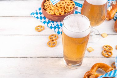 Oktoberfest tebrik kartı geçmişinde iki bira bardağı, tuzlu atıştırmalık ve kraker var. Oktoberfest barı, beyaz ahşap masa üzerindeki kafe menüsü, Ekim Festivali tarzı kareli peçete ve dekorla