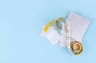 İnce metabolik yamalar, metabolizmayı, enerji artışını ve iştah kontrolünü arttırmak için akıllı kilo kaybı tıbbi biyohack teknolojisi. Ölçüm bandı olan ince yamalar ve mavi arka planda kadın eli