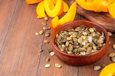 Ev yapımı organik kurutulmuş kabak tohumları taze kabak dilimleri ile ahşap masa zemininde, kopyalama alanı