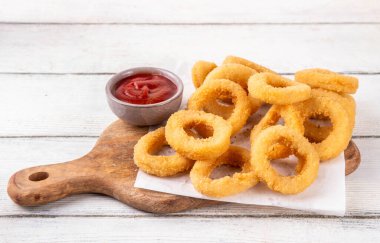 Ketçap soslu altın soğan halkaları, uçak fritözü beyaz ahşap masa fotokopi alanında lezzetli soğan halkaları atıştırmalıkları.