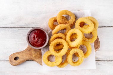 Ketçap soslu altın soğan halkaları, uçak fritözü beyaz ahşap masa fotokopi alanında lezzetli soğan halkaları atıştırmalıkları.