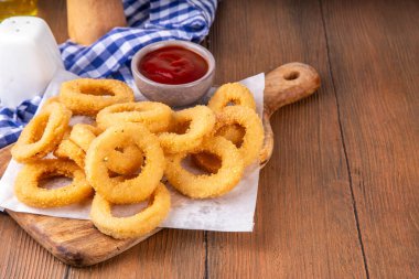 Ketçap soslu altın soğan halkaları, uçak fritözü beyaz ahşap masa fotokopi alanında lezzetli soğan halkaları atıştırmalıkları.