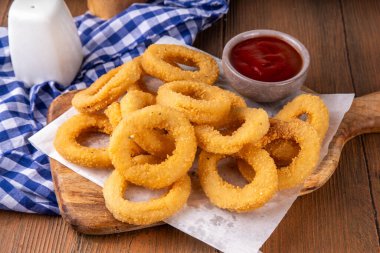 Ketçap soslu altın soğan halkaları, uçak fritözü beyaz ahşap masa fotokopi alanında lezzetli soğan halkaları atıştırmalıkları.