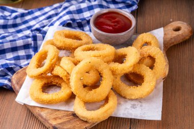 Ketçap soslu altın soğan halkaları, uçak fritözü beyaz ahşap masa fotokopi alanında lezzetli soğan halkaları atıştırmalıkları.