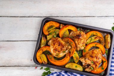 Kavrulmuş fırında tavuk budu, balkabağı ve patates dilimleri, sarımsak ve aromalı bitkiler. Lezzetli sonbahar konforlu yemekleri, Şükran Günü aile yemeği fikirleri.