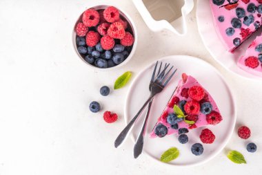 Yaz meyveli ve fırınlanmamış peynirli kek. Kremalı pasta ve çikolatalı kek, pembe peynir tabakası, yabanmersini, ahududu, çilek, nane yaprağı, beyaz masa fotokopisi alanı.