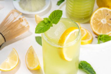 Buzlu Matcha Limonata kokteyli. Yeşil buzlu kibrit çayı, limon dilimleri ve beyaz arka planda taze nane ile karıştırılmış içecek. 