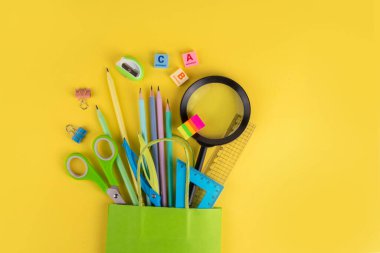 Okul satışına ve alışveriş konseptine geri dönelim. Okul kırtasiyesindeki kalemler, boyalar, makas, defterler, hesap makinesi, okul gereçleri, renkli arka planda öğrenim ürünleri 