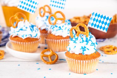 Oktoberfest kekleri tuzlu kraker, krem şanti ve renkli şeker serpintileri, beyaz ahşap arka planda Oktoberfest bayram dekoru, kopyalama alanı