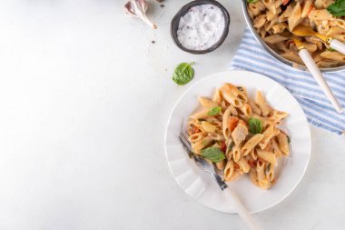 Son moda viral benimle tavuk makarnası evlen. Bir tencere yumuşak makarna ve kremalı ve peynirli sulu tavuk parçaları, sarımsaklı güneşte kurutulmuş domates sosu, nükteli fesleğen yaprağı, tabak ve demlikte.