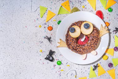 Fun Halloween Donuts. Creative decoration for chocolate donuts on Halloween  decorated table. Treat or trick holiday kid snack, white table background copy space