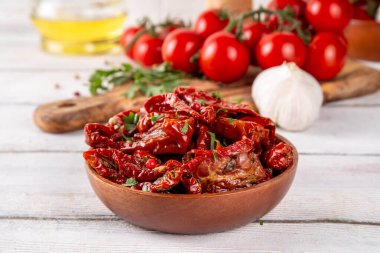 Zeytin yağında ev yapımı kurutulmuş domatesler, gurme İtalyan yemekleri, taze domates, yağ şişesi ve mutfak masasında baharatlar.