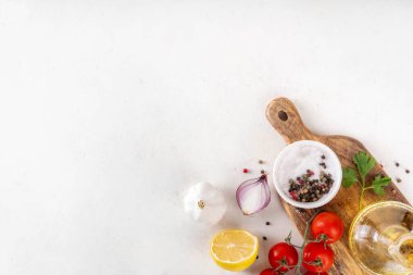 Baharatlar, karabiber, sarımsak, soğan, yeşillik ve domates, beyaz yemek masasında zeytin yağı. Beyaz taş arkaplanda yemek pişirmek için gerekli malzemeler..
