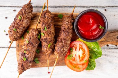 Çubuklu şiş kebap, kıymalı kıymadan yapılır. Lula kebap, geleneksel Kafkas yemeği, ketçap, baharat ve sebze salatası, barbekü ızgara pişirme arka planı fotokopi alanı yukarıda. 