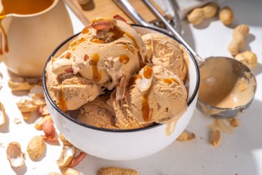 Fıstık ezmeli dondurma topları. Bir sürü fındık dondurması seramik kasede karamelli sos, beyaz mutfak arka plan fotokopi alanı.