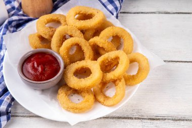 Ketçap soslu altın soğan halkaları, uçak fritözü beyaz ahşap masa fotokopi alanında lezzetli soğan halkaları atıştırmalıkları.