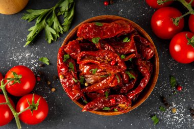 Zeytin yağında ev yapımı kurutulmuş domatesler, gurme İtalyan yemekleri, taze domates, yağ şişesi ve mutfak masasında baharatlar.