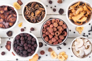 Dondurulmuş meyveler, yaz hasadını depolamak için alternatif bir yol. Kurumuş kurutulmuş ahududu, yabanmersini, şeftali, muz, kayısı, erik, böğürtlen, elma, beyaz ahşap arka planda kiraz.