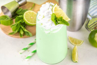 Limonlu turta ya da mojito soğuk milkshake kokteyli. Krem şantili, naneli ve limonlu tatlı ekşi kremalı içecek, beyaz ve yeşil limonlu parlak arka plan. 