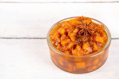 Ev yapımı tatlı sonbahar balkabağı Chutney, kahverengi şekerli, tarçınlı, beyaz ahşap zemin üzerinde - kabak kabağı, baharatlar, bal