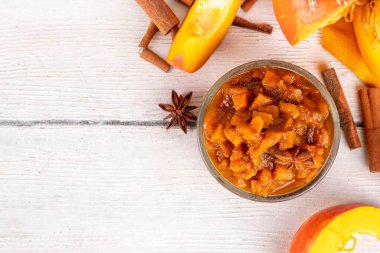 Ev yapımı tatlı sonbahar balkabağı Chutney, kahverengi şekerli, tarçınlı, beyaz ahşap zemin üzerinde - kabak kabağı, baharatlar, bal