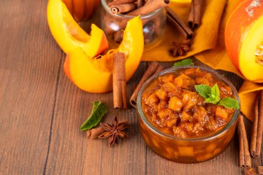 Ev yapımı tatlı sonbahar balkabağı Chutney, kahverengi şekerli, tarçınlı, beyaz ahşap zemin üzerinde - kabak kabağı, baharatlar, bal