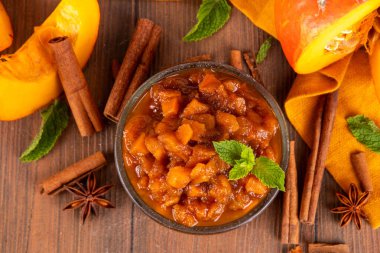 Ev yapımı tatlı sonbahar balkabağı Chutney, kahverengi şekerli, tarçınlı, beyaz ahşap zemin üzerinde - kabak kabağı, baharatlar, bal