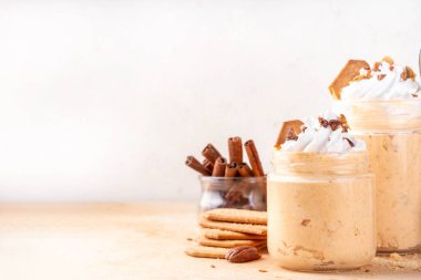 Kremalı, fındıklı ve krakerli yulaf ezmeli balkabağı turtası. Lezzetli kremalı balkabağı baharatlı yulaf, bej arka planda baharat ve dekoratif balkabakları, kopyalama alanı