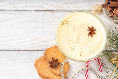 Noel kahvaltısı, Eggnog Yunan yoğurdu. Bir kase yoğurt, yumurta sarısı, hindistan cevizi, vanilya ve baharatla çırpılmış, Noel süslemeli arka planda. Lezzetli, protein açısından zengin sağlıklı eggnog versiyonu.