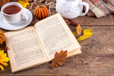 Sonbahar mevsiminde sıcak kahvaltı, bahçede erken sonbahar çayı, balkabağı mumları ve dekorlu taze demlenmiş çay fincanı, sonbahar yaprakları ve açık kitap, okuma zamanı sakin hayat