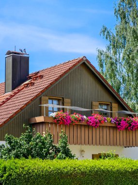 Evin üst kısmında açık balkon, çiçekler, çatı bacası ve huş ağacı var. Yüksek kalite fotoğraf