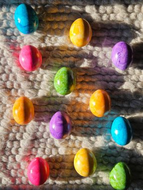 Brightly colored Easter eggs on textured wool rug in sunlight. Vibrant spring holiday backdrop. High quality photo clipart