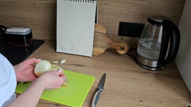 Mutfakta soğan soymak. Malzemeler hazırlanıyor. Kadınların elleri mutfakta soğan soyarken.