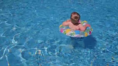 Mutlu sarışın çocuk havuzda yüzüyor. Çocuk yüzüyor. Yaz tatili, mutlu hatıralar konsepti. Yüksek kalite 4k görüntü