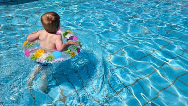 Havuzda yüzen sarışın bebeğin arka manzarası. Ananas yüzme yüzüğü. Yaz havası ve kaygısız bir tatil. Yüksek kalite fotoğraf