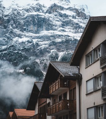 Grindelwald, İsviçre 'deki karlı kış dağlarının altında eski ahşap evler..