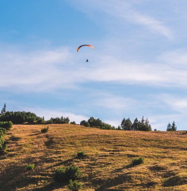 Güney Almanya 'daki Bavyera Alpleri' nin tepesinde bir paraglider. Gökyüzü açık ve mavi.