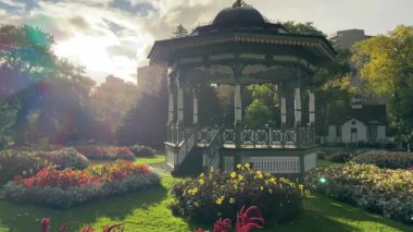 Halifax Halk Bahçeleri. Parkta güneşli bir sabah, hafif yağmur, çiçekli güzel yeşil bir park ve turist çardağı, yavaş çekim. Yüksek kalite 4k görüntü