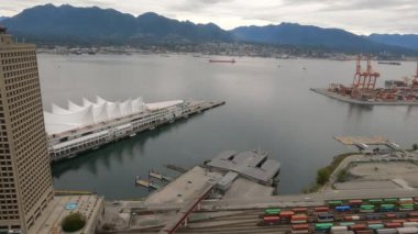 Bulutlu bir havada Vancouver 'ın 4K' lık zaman çizelgesi ve boğazdan geçen bir gemi. Manzara ikonik Kanada Meydanı 'nı, çevreleyen dağları ve hareket halindeki iskele vinçlerini yakalar. Şey...